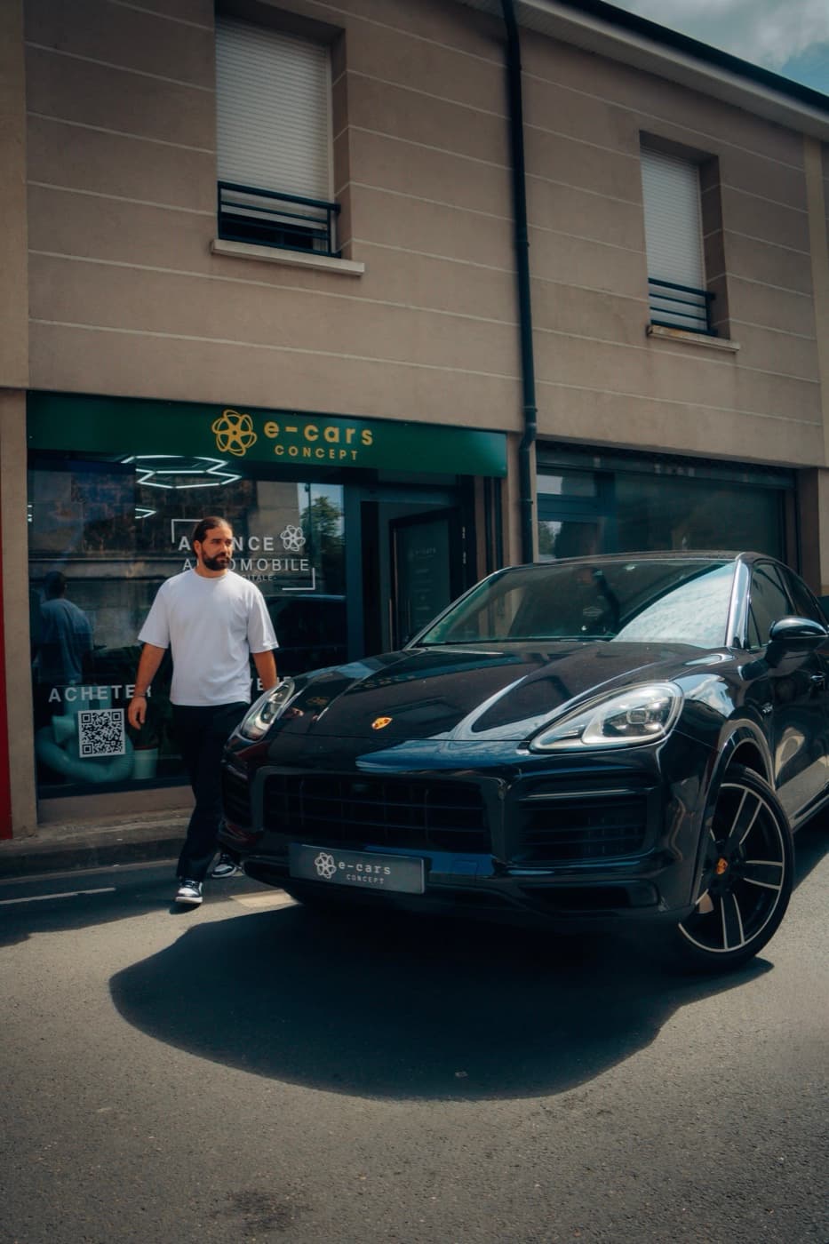 Devanture d'une agence E-Cars Concept, une Porsche Cayenne noire garée devant